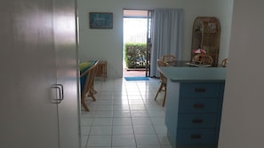 Ein Zimmer mit Essbereich, einem blauen Schrank und Blick auf einen Garten durch eine Tür.