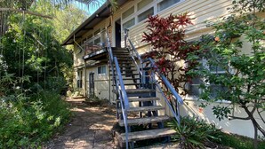 A house with a staircase leading to a garage, surrounded by lush greenery. - The Captain's Manor On Cook 5 (Arcadia)