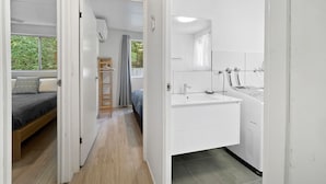 A compact room with a bed, a small kitchenette, and a bathroom.