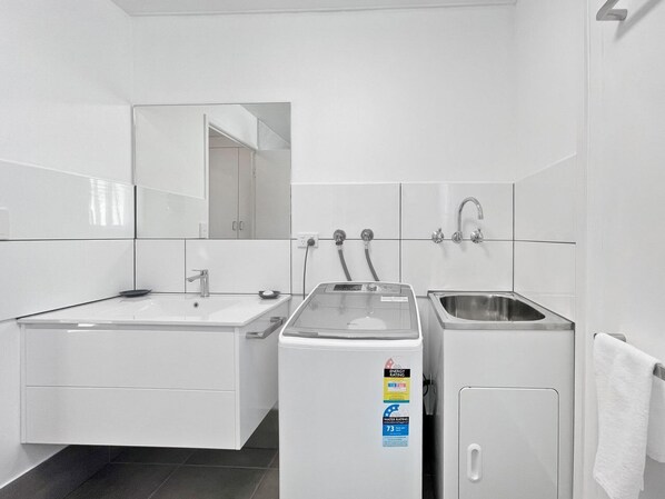 Une salle de bain moderne équipée d’un lavabo, d’un miroir et d’un chauffe-eau.