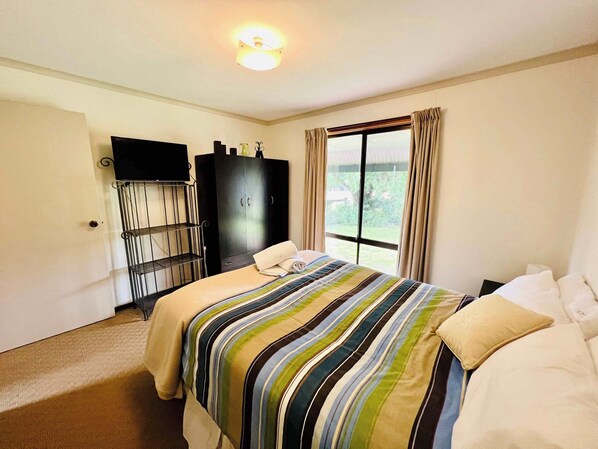 Une chambre d’hôtel avec un lit, une armoire, une télévision et une fenêtre avec des rideaux.