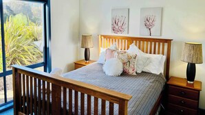 Camera da letto con un letto, una testiera in legno, comodini, lampade e opere d'arte appese al muro.