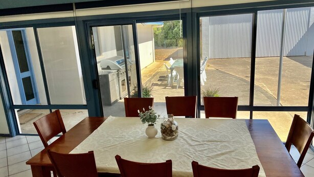 A dining area with a table and chairs, large windows, and a view of the outside. - Blue Poles -Temporary Not Pet Friendly (Robe)