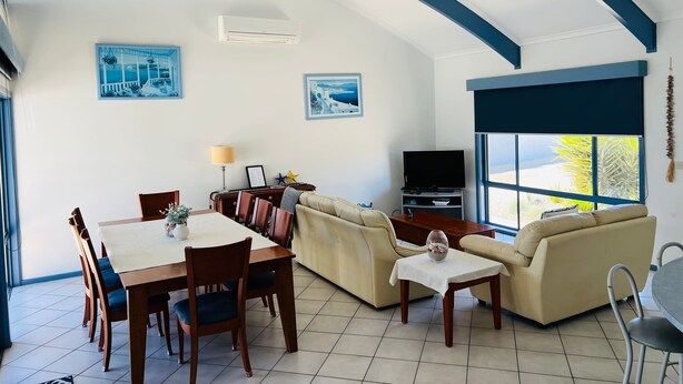 Un soggiorno con zona pranzo, un divano, una TV e un'ampia finestra con vista.