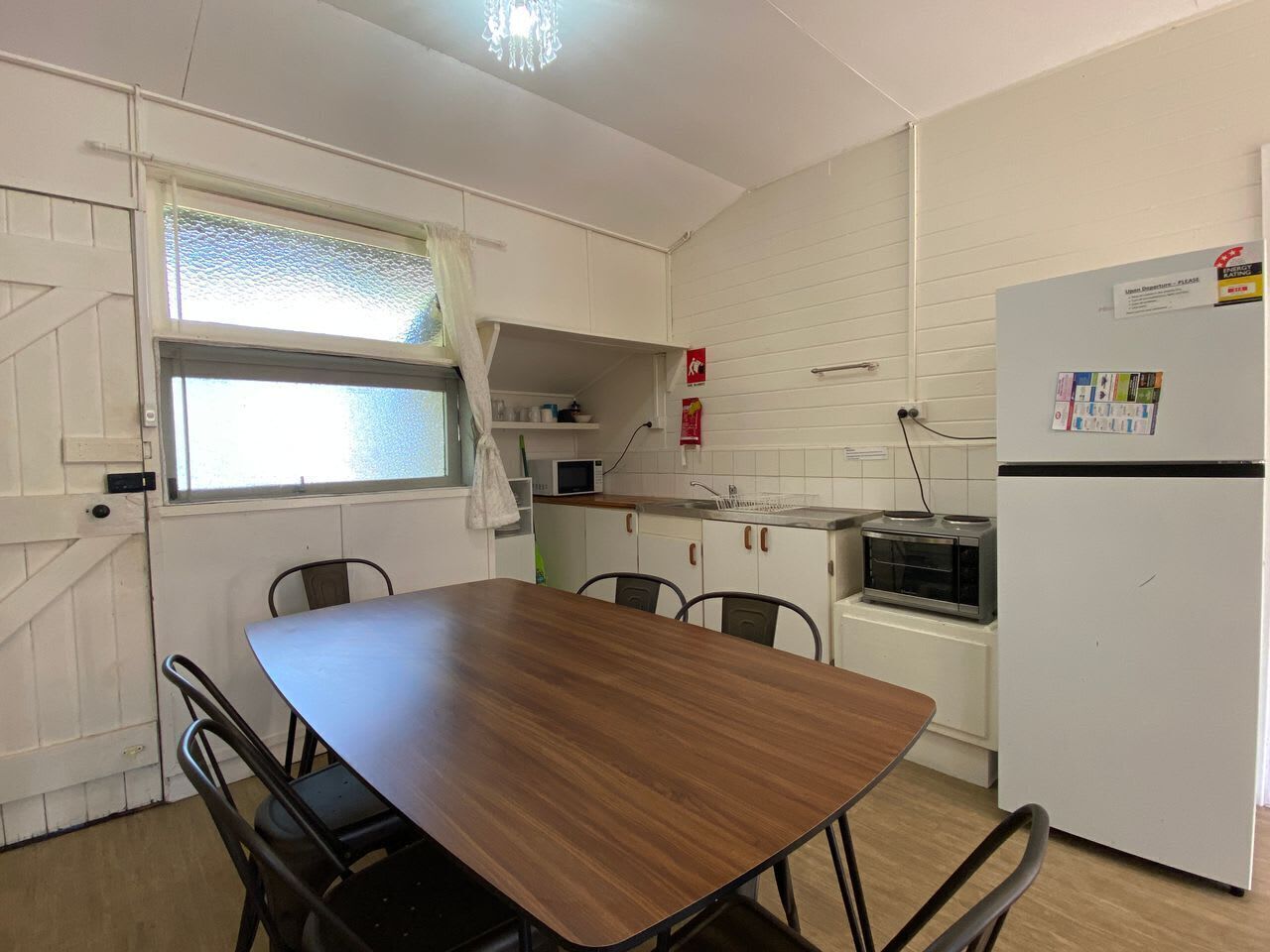 Une cuisine compacte comprenant une table à manger, des chaises, un réfrigérateur, un four à micro-ondes et un petit four.