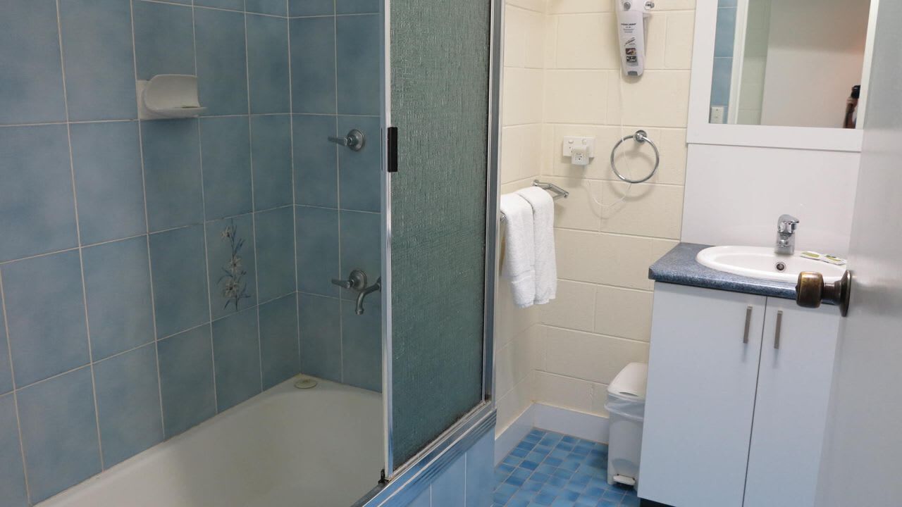 Un bagno con doccia, wc, lavandino e specchio.