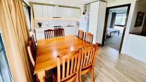 Uma cozinha moderna com armários brancos, uma mesa de jantar de madeira e cadeiras.