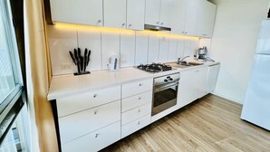 Uma cozinha moderna com armários brancos, fogão a gás, forno e pia.
