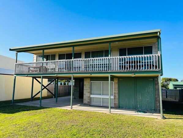 A two-story building with a balcony, a garage, and a fenced yard. - Just A Glimpse Shack -Avail. Oct LWknd - Pet friendly outside (Robe)