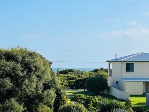 A modern two-story house with a flat roof, surrounded by lush greenery and a clear sky. - Just A Glimpse Shack -Avail. Oct LWknd - Pet friendly outside (Robe)