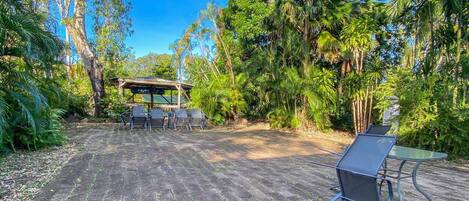 Un patio al aire libre con un área de estar techada, una mesa y sillas.