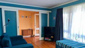 Un salon avec un canapé, un téléviseur, un lit et un plancher en bois.