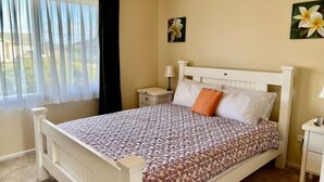 Une chambre à coucher avec un lit, une table de chevet, une lampe et une fenêtre avec des rideaux.