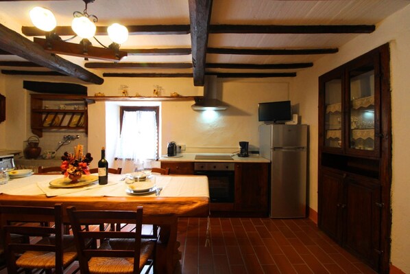 Eine Küche mit Holztisch, Stühlen, Herd, Kühlschrank und einem Fenster.