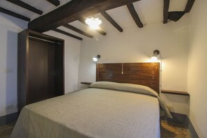 Une chambre à coucher avec une tête de lit en bois, un lit recouvert d’une couvre-lit de couleur claire et deux lampes de chevet.