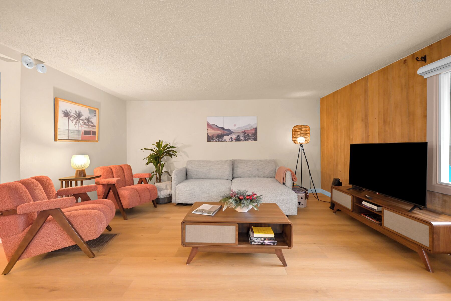 A living room with a sofa, two armchairs, a coffee table, a TV, and a lamp.