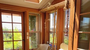 Una habitación soleada con paredes de madera, un ventanal grande y dos sillas.