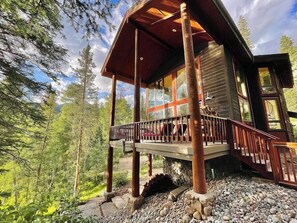A wooden cabin with a balcony, surrounded by trees and a stone pathway. - Mountain Getaway- Hot Tub, Hiking, 5mins to Ski Resort (Durango)