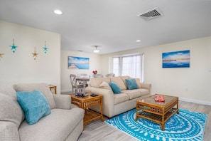 A living room with a sofa, coffee table, and wall art. - Large Home | Dog OK | Heated Pool | Close to Beach (Sarasota)