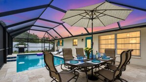 Eine überdachte Terrasse mit Pool, Essbereich im Freien und Blick auf das Haus.
