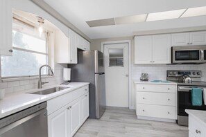 A modern kitchen with white cabinetry, stainless steel appliances, a dishwasher, and a microwave. - Large Home | Dog OK | Heated Pool | Close to Beach (Sarasota)