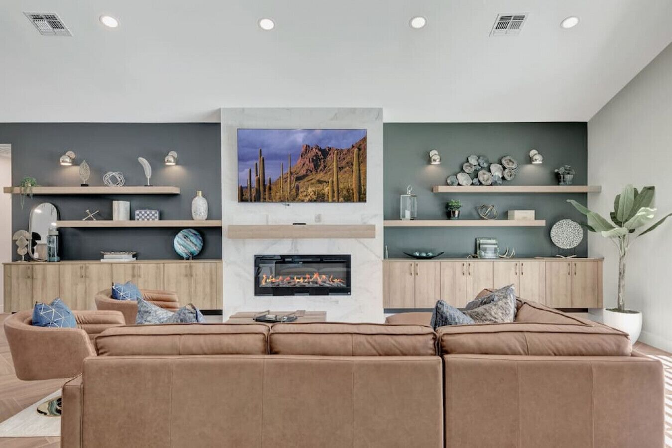 Un salon moderne avec une cheminée, un grand téléviseur à écran plat et un ensemble de canapés.
