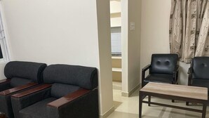A living room with a dark grey sofa, two black leather armchairs, and a wooden coffee table.