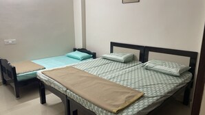 A room with two single beds, a wooden headboard, a beige blanket, and a framed picture on the wall.