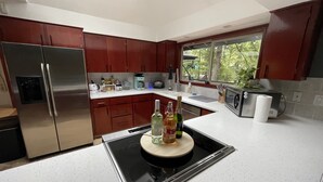 Een moderne keuken met roestvrijstalen apparatuur, houten keukenkastjes en een centraal kookeiland met flessen.