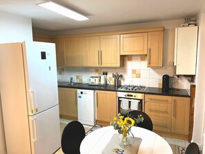 Una cocina compacta con armarios de madera, un refrigerador blanco, una estufa a gas y un lavamanos.