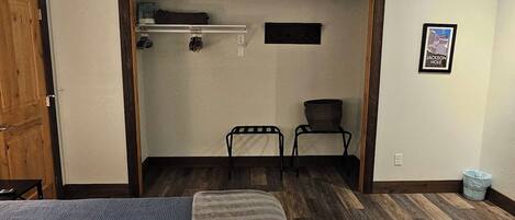 Une chambre à coucher avec un lit, une chaise, une étagère avec quelques objets et un tableau au mur.