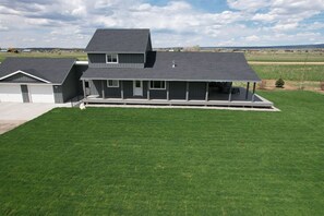 A two-story house with a covered porch and a well-maintained lawn. - Alpenglo Farm with Event Space and Parking (Driggs)