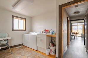 A laundry area with a washing machine, dryer, and a small table with cleaning supplies. - Alpenglo Farm with Event Space and Parking (Driggs)