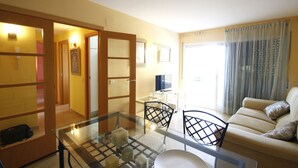 Una sala de estar con una mesa de vidrio, dos sillones, un sofá y un televisor.