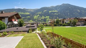 Un quartier résidentiel avec des maisons, une pelouse verdoyante et des montagnes en arrière-plan.