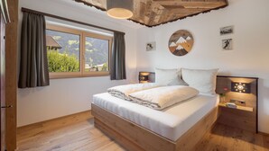 Une chambre avec un lit en bois, une grande fenêtre et une vue sur les montagnes.