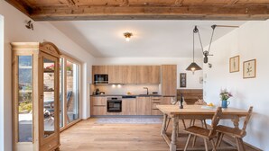 Une cuisine moderne avec des meubles en bois, une table à manger avec des chaises et une grande fenêtre donnant sur l’extérieur.