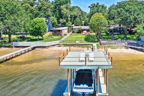 A boat docked at a pier with a view of a residential area and a large tree. - Lakefront Mabank Gem w/ Sunset Views: Pets Welcome (Mabank)