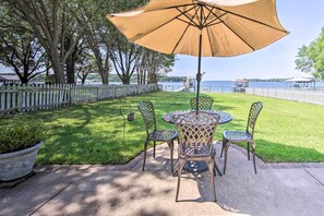 A patio with a round table and chairs, an umbrella, and a view of a lake. - Lakefront Mabank Gem w/ Sunset Views: Pets Welcome (Mabank)