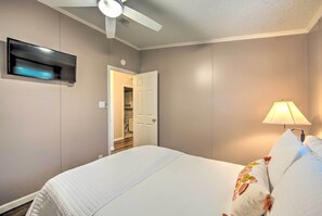 A bedroom with a bed, a ceiling fan, a TV mounted on the wall, and a door leading to a hallway. - Lakefront Mabank Gem w/ Sunset Views: Pets Welcome (Mabank)