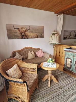 A cozy room with a woven sofa, a small wooden table with a vase, and a cabinet with decorative doors.