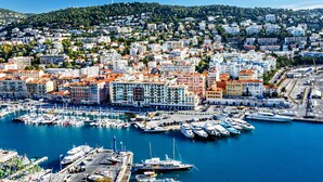 A coastal cityscape with a marina filled with boats, surrounded by densely packed buildings with varied architecture. - Charming Flat Saleya OLD Town (Nice)