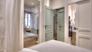 A bedroom with a bed, a bedside table, and a window. There are two doors leading to other rooms. - Charming Flat Saleya OLD Town (Nice)