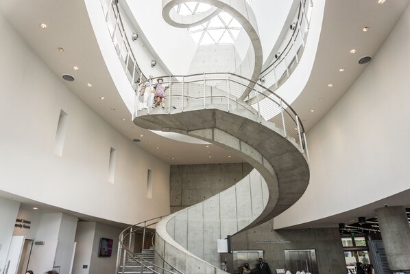 A modern interior with a central spiral staircase, high ceilings, and a skylight.