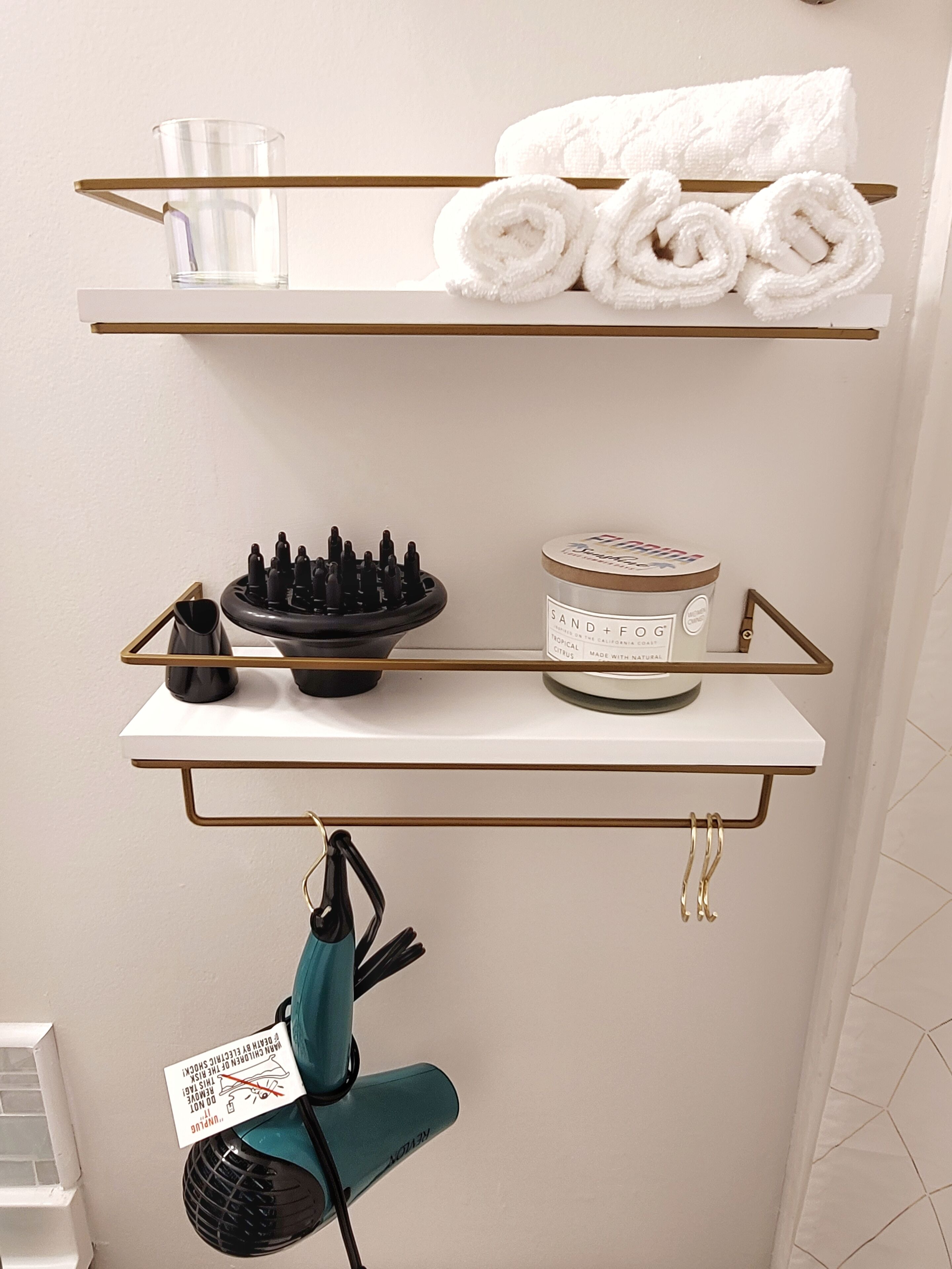 Een badkamer met een wit aanrecht, een handdoekhouder, een glas, een schaaltje toiletartikelen en een handdoek.