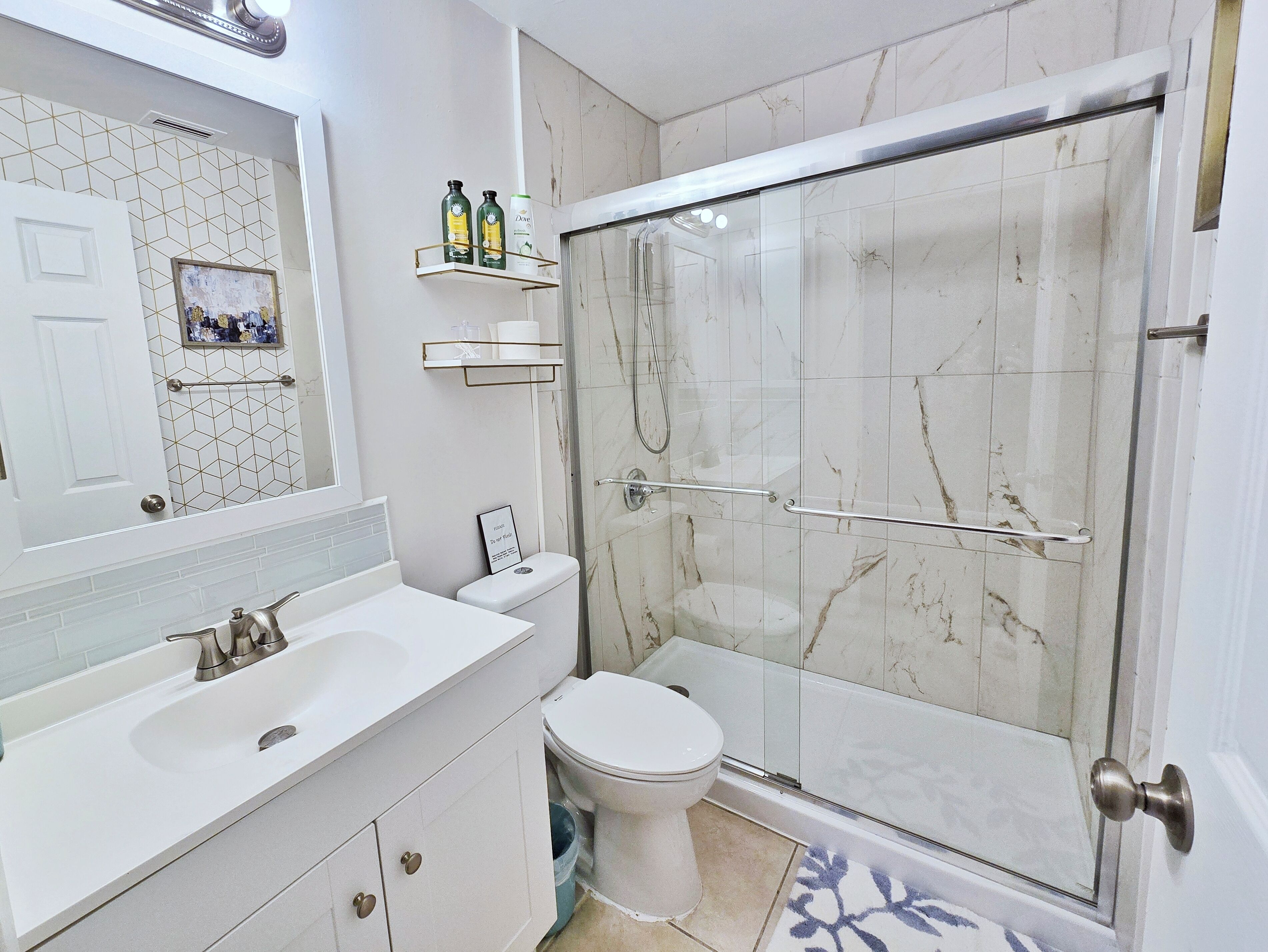 A modern bathroom with a white sink, toilet, and shower area.