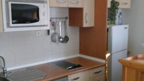 A compact kitchen with a microwave, sink, dishwasher, and a small refrigerator.