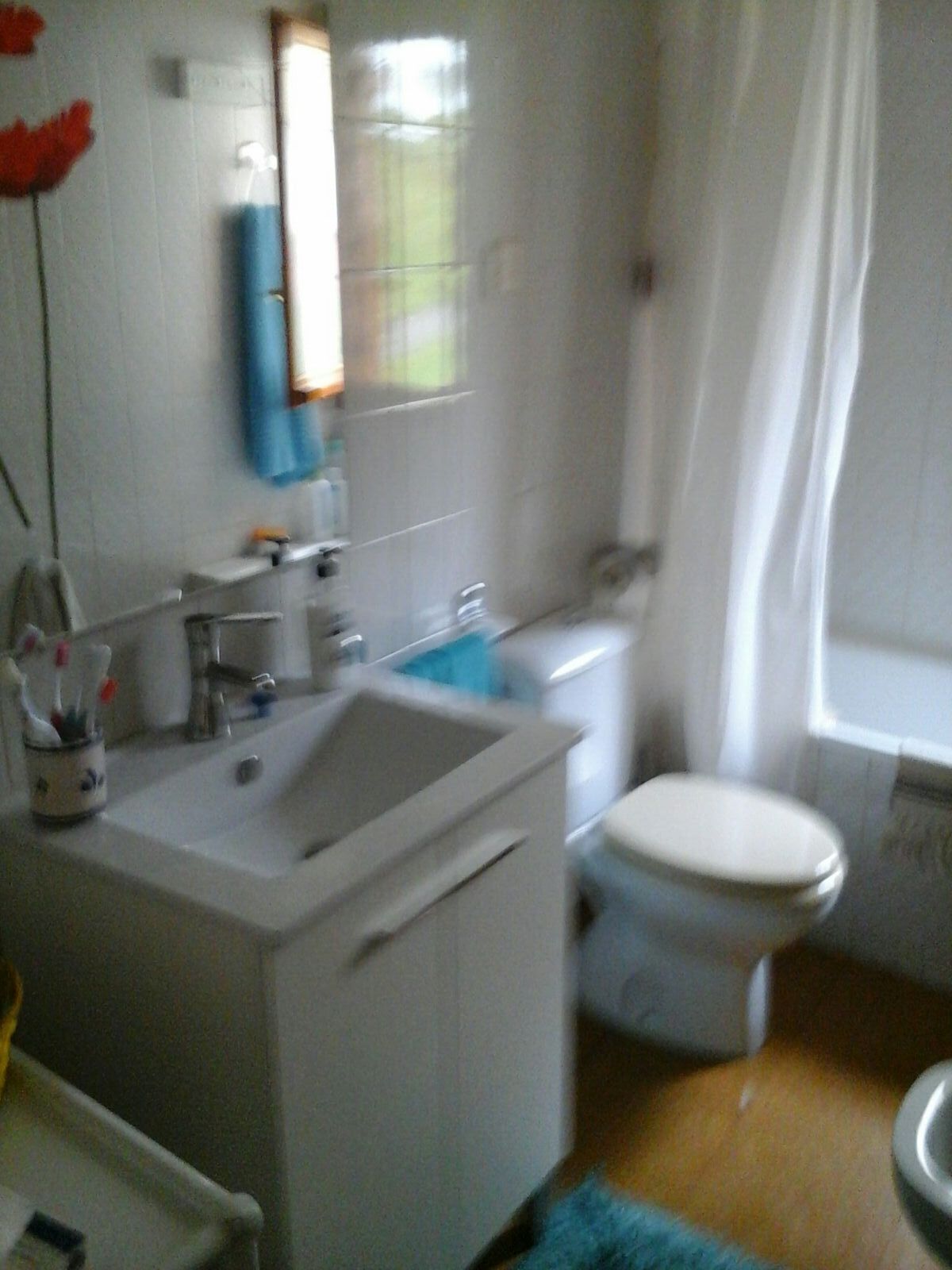Casa de banho com lavatório branco, sanita e zona de duche.