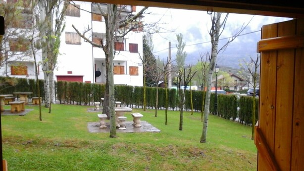 A courtyard with a wooden fence, stone tables, and a building in the background.