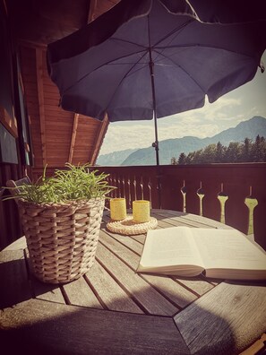 A wooden deck with a woven basket of green plants, two yellow candle holders, and an open book. - Apartment - 4 persons+, 70sqm, 2 bedrooms, balcony, eat-in kitchen, unique location, WLAN (Anger)
